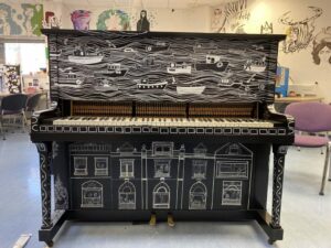 black piano with white boats and houses painted on